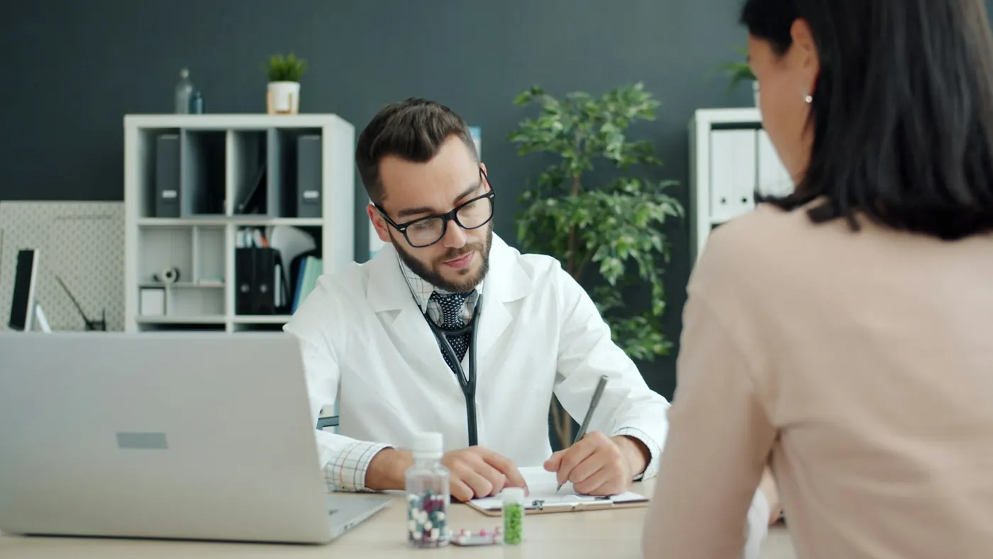 A doctor taking notes with a patient
