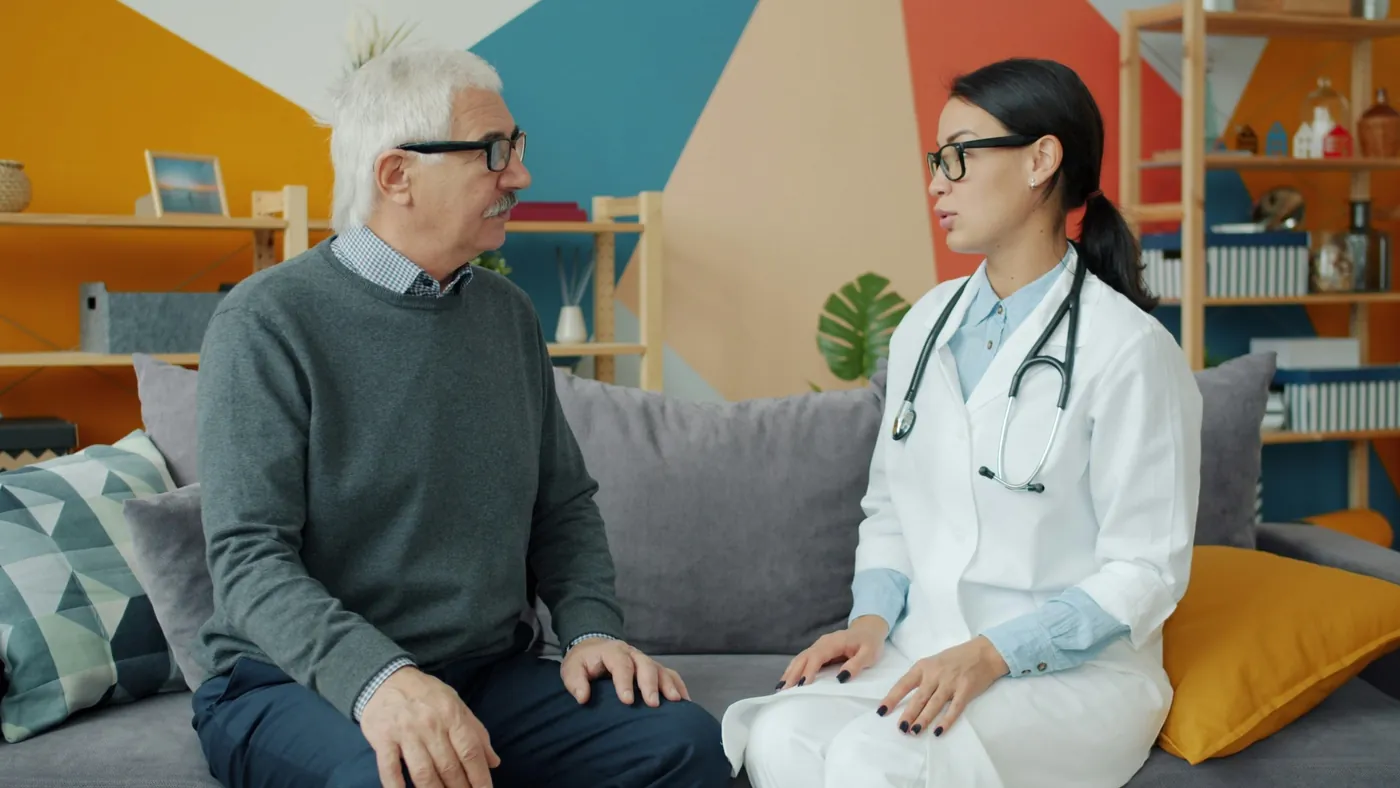 A doctor talking with an older patient at home